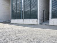 the black skateboard is in front of a tall building with lots of windows and concrete