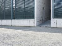 the black skateboard is in front of a tall building with lots of windows and concrete