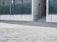 the black skateboard is in front of a tall building with lots of windows and concrete
