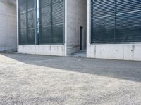 the black skateboard is in front of a tall building with lots of windows and concrete