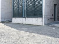 the black skateboard is in front of a tall building with lots of windows and concrete
