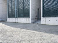 the black skateboard is in front of a tall building with lots of windows and concrete