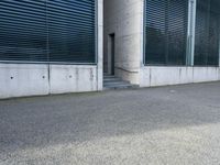 the black skateboard is in front of a tall building with lots of windows and concrete