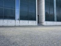 the black skateboard is in front of a tall building with lots of windows and concrete