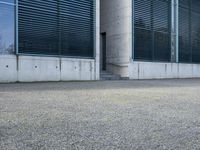 the black skateboard is in front of a tall building with lots of windows and concrete