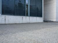 the black skateboard is in front of a tall building with lots of windows and concrete