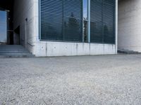 the black skateboard is in front of a tall building with lots of windows and concrete
