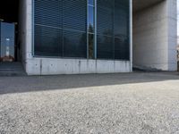 the black skateboard is in front of a tall building with lots of windows and concrete