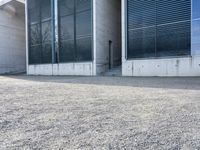 the black skateboard is in front of a tall building with lots of windows and concrete