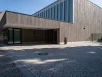 the back side of the building is made of wooden and glass and has a driveway between the buildings