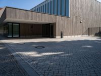 the back side of the building is made of wooden and glass and has a driveway between the buildings