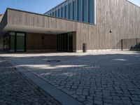 the back side of the building is made of wooden and glass and has a driveway between the buildings