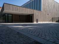 the back side of the building is made of wooden and glass and has a driveway between the buildings