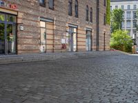 a motorcycle is driving down an empty street in a city corner, with cobblestone street