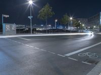 city lights shine brightly on a dark, empty street at night with bikes and bicycles in the bike lane