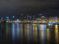 view over the city lights reflected on water of a river at night with building cranes