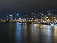 view over the city lights reflected on water of a river at night with building cranes