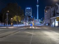 a city street is lined with trees, buildings and cars at night time near a light pole