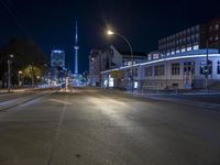 a city street is lined with trees, buildings and cars at night time near a light pole