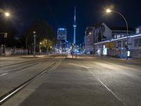 a city street is lined with trees, buildings and cars at night time near a light pole