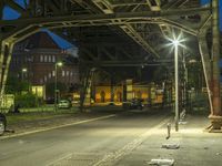 the sidewalk in front of a train station at night with streetlights and cars on the side of it