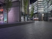 a walkway through a park with trees in the background at night time in front of an office building