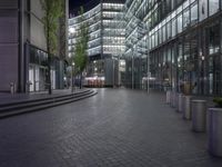 a walkway through a park with trees in the background at night time in front of an office building