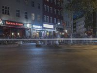 a water fountain gusging through the streets by buildings at night on a city street