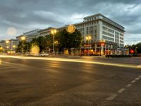 a street with lights turning on a rainy evening in berlin, germany at night time