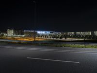 a street lit up by lights at night next to an airport, with a ramp