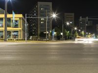 a street at night with lights and buildings in the background by the roadways of the streets