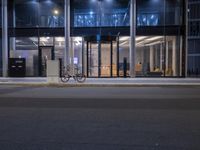 a bicycle is propped up against a sign in front of a building at night time