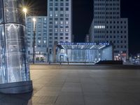 there is a big glass structure in the middle of the city at night time with a street light