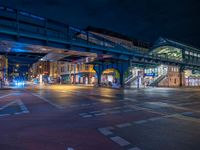 the empty street is filled with people walking and biking under an overpass at night