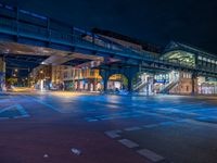 the empty street is filled with people walking and biking under an overpass at night