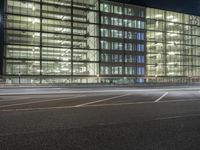 an empty lot in front of a building with windows at night on a clear day