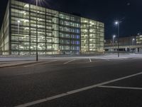 an empty lot in front of a building with windows at night on a clear day