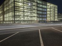 an empty lot in front of a building with windows at night on a clear day