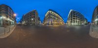 this is an 360 - view of some buildings near the road at night time or evening