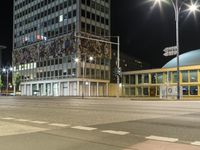 cars are traveling around a city street at night time with lights on the side of a building