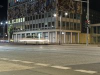 cars are traveling around a city street at night time with lights on the side of a building