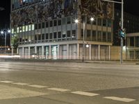 cars are traveling around a city street at night time with lights on the side of a building