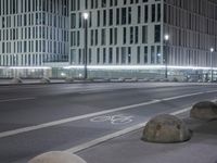 a picture of a concrete ball on the side of a road at night by some buildings