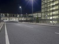 the empty road next to an office building is seen during the night hour, with two rows of windows that extend into the space