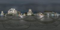 a circular glass panoramic photograph of buildings in a town square at night,