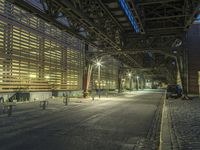 a long street with traffic under an overpass at night, in the evening time