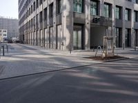empty street with a tree branch next to an office building with a water spout and ladder in it