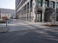 empty street with a tree branch next to an office building with a water spout and ladder in it