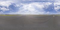 a blue sky with white clouds and an intersection on a paved runway in the middle of the picture