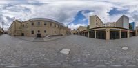 a panoramic view of a courtyard with a sky background and some buildings on either side